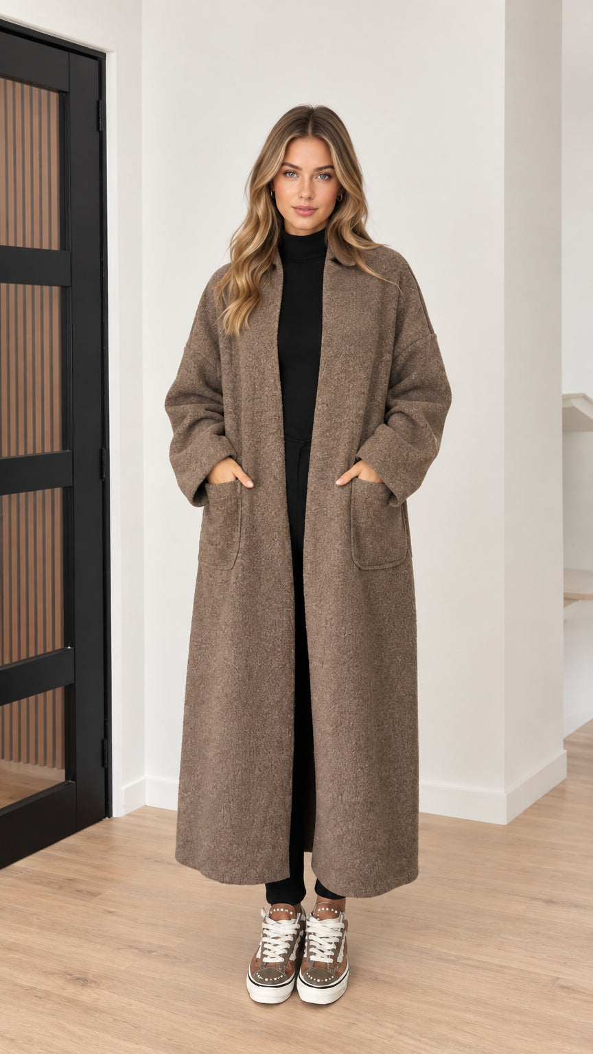 Front view of model wearing taupe brown longline textured coat with lapels and patch pockets