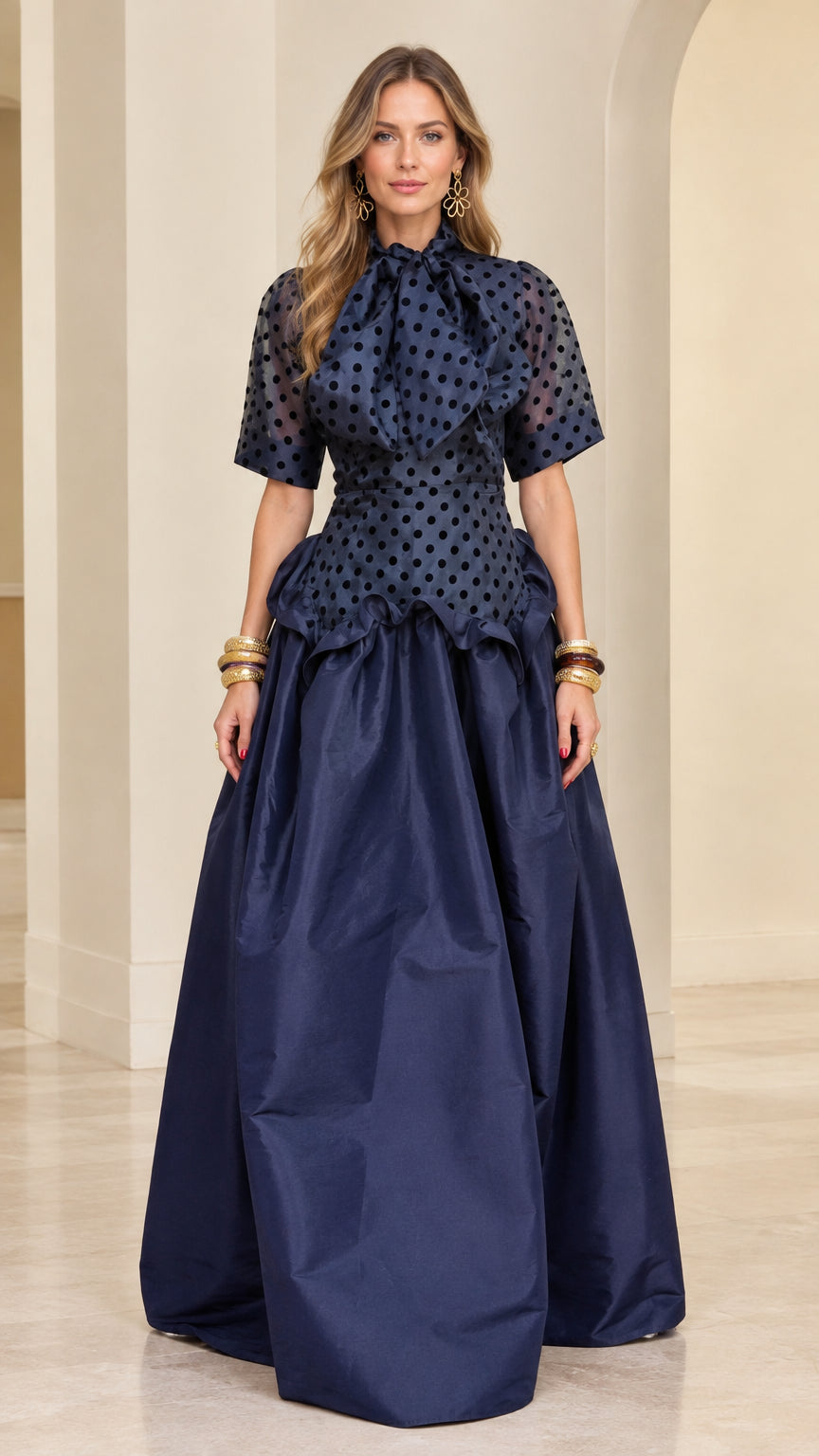 Model wearing navy blue polka dot bow neck peplum evening gown - front view