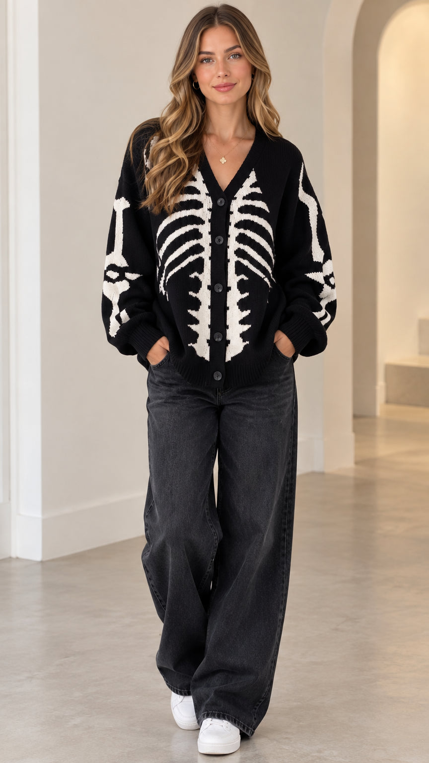 Front view of model wearing black skeleton graphic knit button-front cardigan with wide-leg jeans