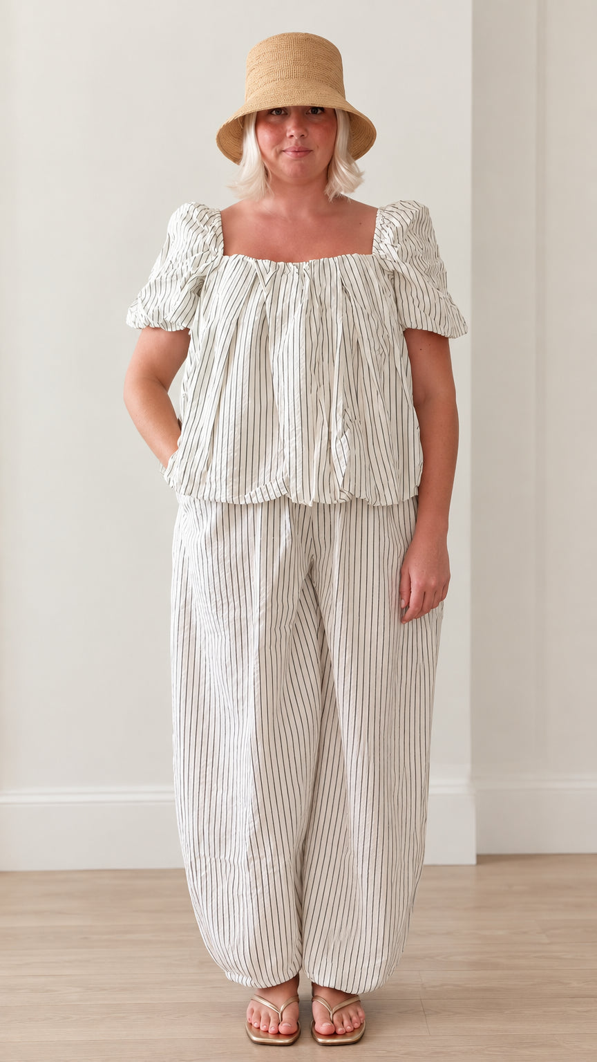 Front view of woman wearing white striped square neck puff sleeve top and lantern pants set