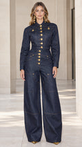 Front full-length view of woman wearing dark blue wide-leg denim jumpsuit with gold buttons