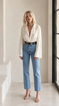 Front full view of woman wearing cream lapel V-neck flare sleeve blouse with jeans