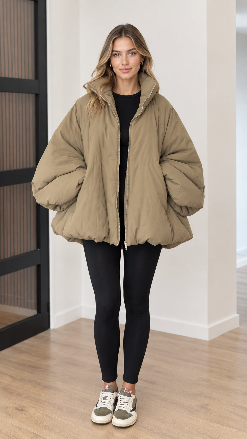 Front view of model wearing oversized khaki cocoon puffer jacket with black leggings and sneakers