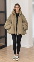 Front view of model wearing oversized khaki cocoon puffer jacket with black leggings and sneakers