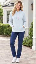 Front view of a blonde model wearing a light blue drawstring hoodie paired with navy pants