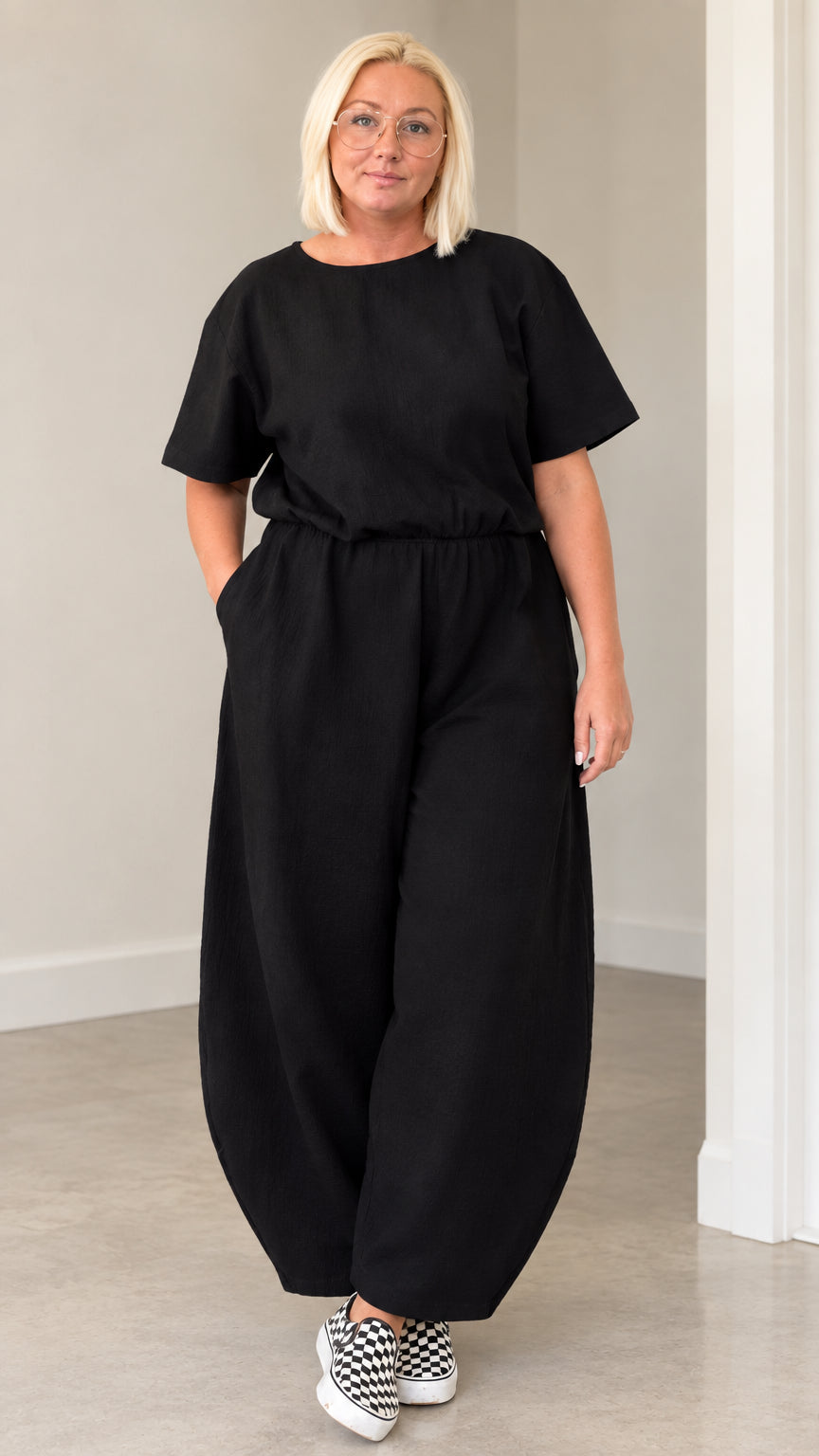 Front view of woman wearing black casual short sleeve lantern leg jumpsuit