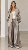 Front full-length view of woman wearing taupe silky jacket and matching wide-leg trousers