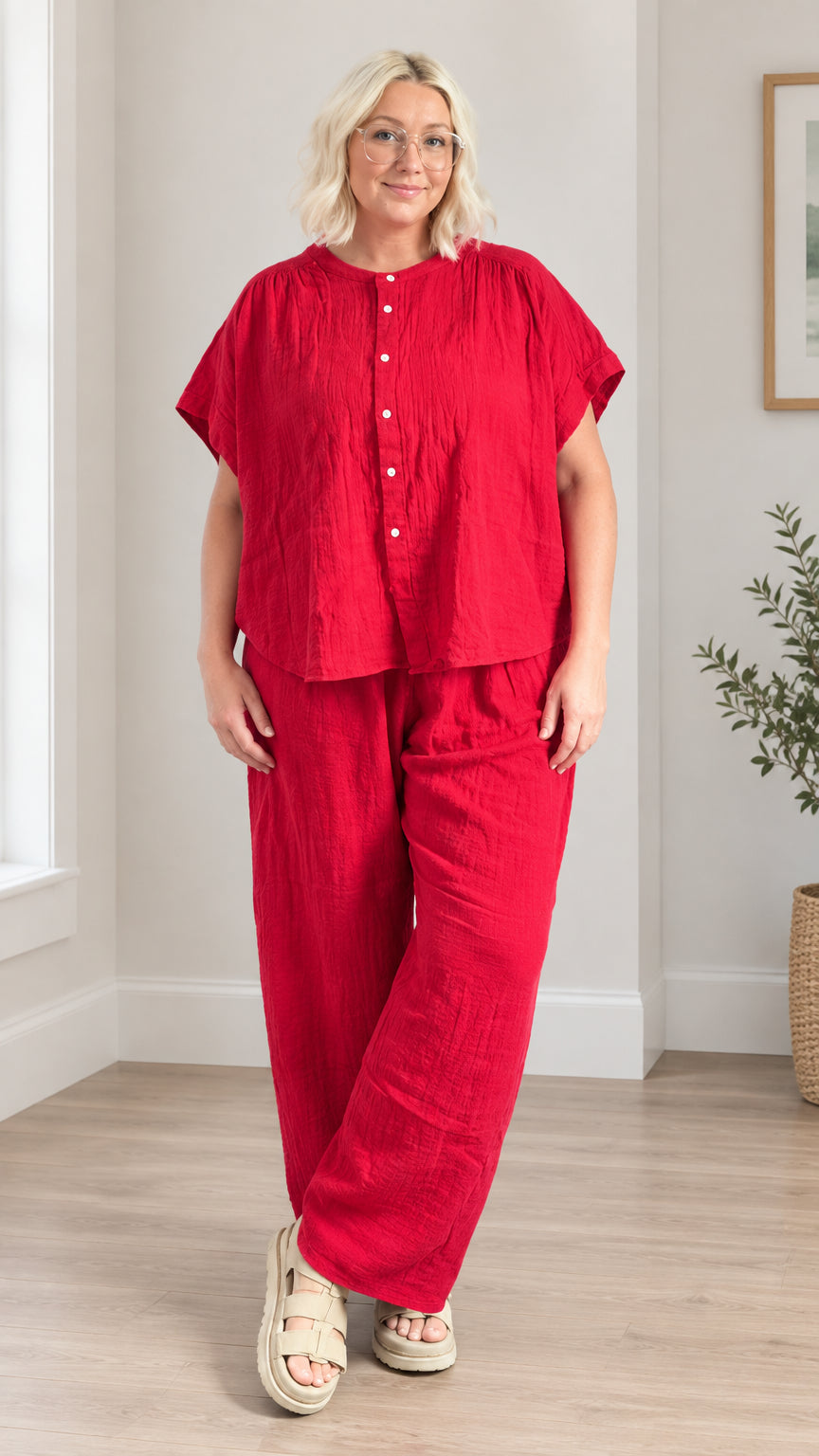 Front full-length view of model wearing red short sleeve button-front top and wide leg pants set