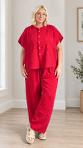 Front full-length view of model wearing red short sleeve button-front top and wide leg pants set