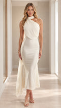 Front full view of woman wearing ivory high-neck draped one-shoulder mermaid midi dress