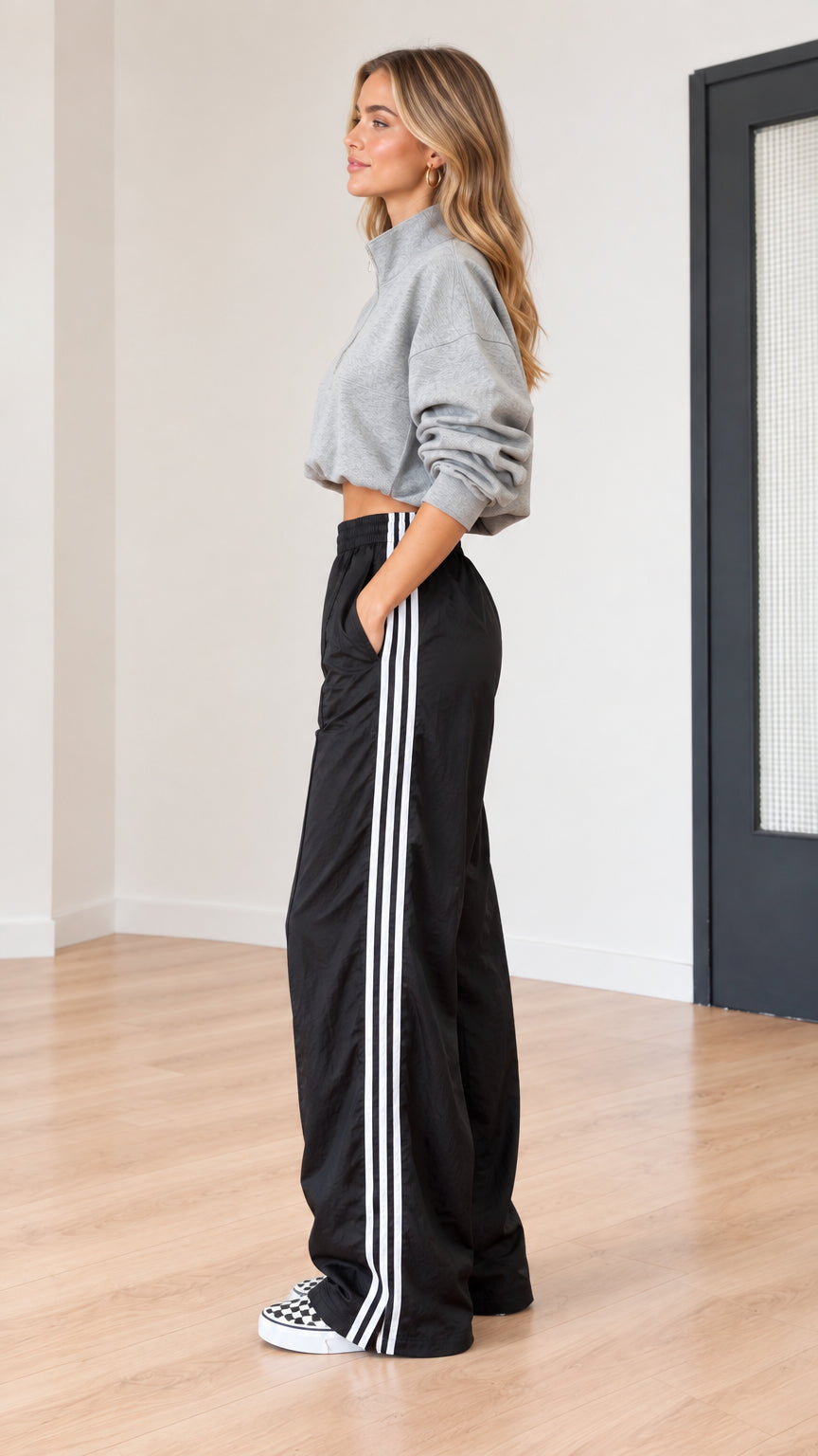 Side profile of model in grey cropped half-zip top and black side-stripe pants