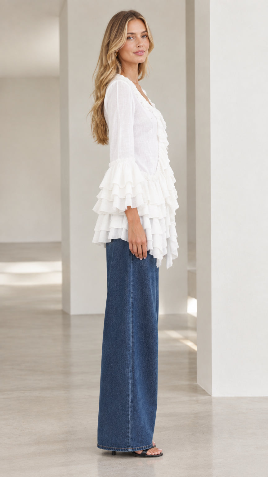 Side profile of model wearing white ruffled bell sleeve blouse