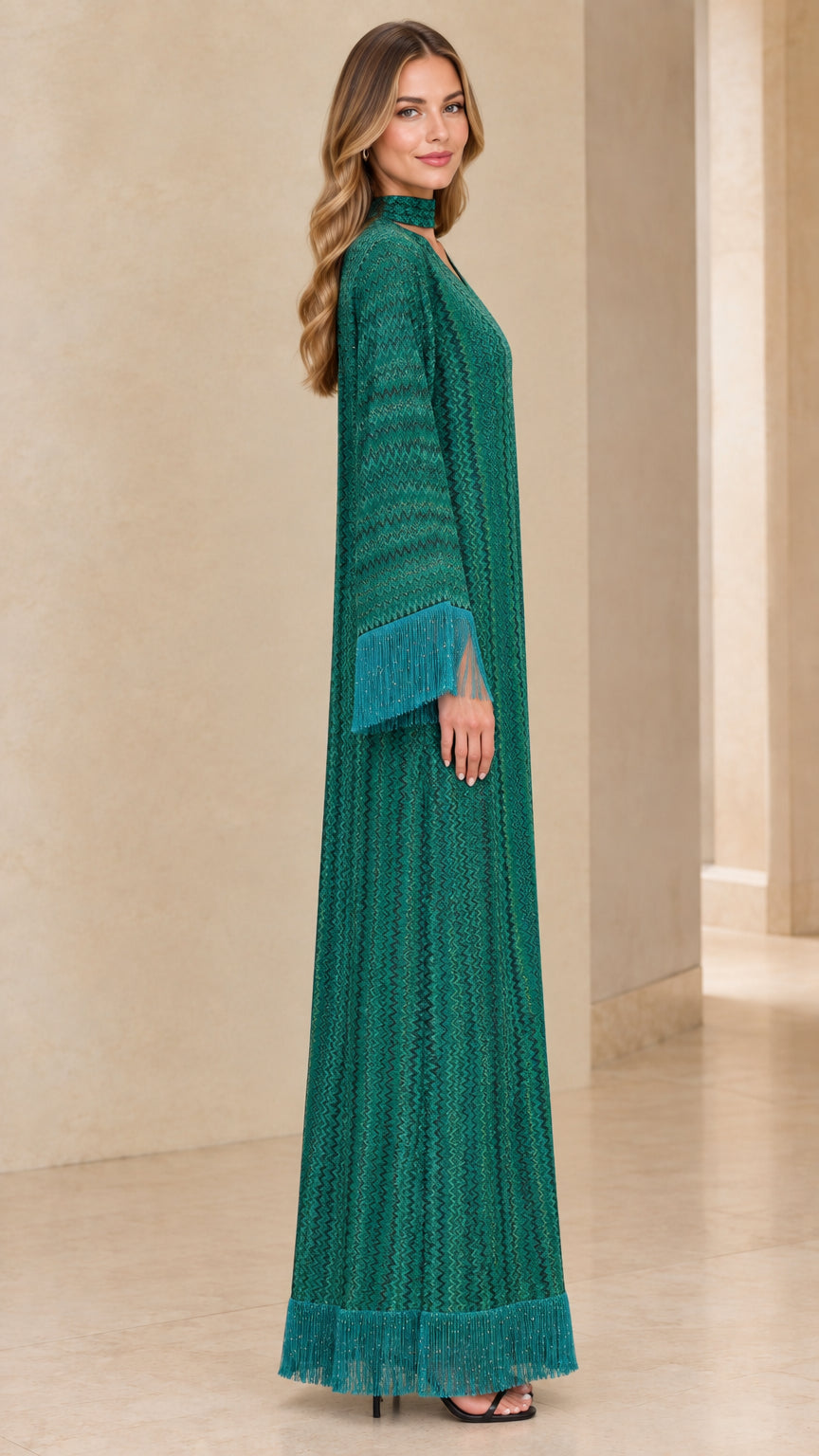 Side full view of woman in emerald green textured maxi dress showcasing fringe hem and sleeve cuffs