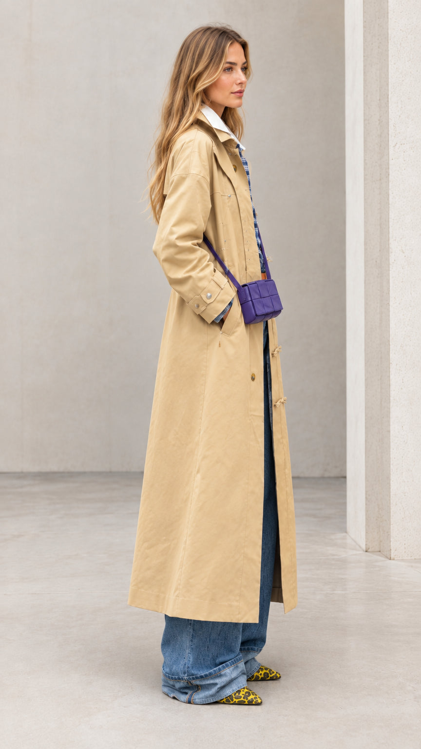 Side profile view of woman modeling khaki long duster trench coat