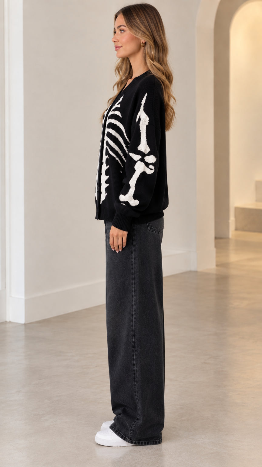 Side profile view of model wearing black skeleton knit cardigan sweater with long graphic sleeves
