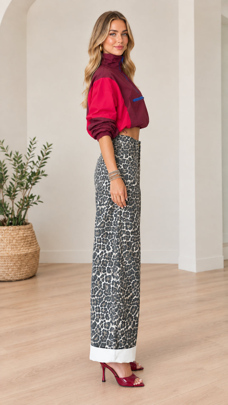 Side profile view of woman wearing burgundy cropped windbreaker and leopard print wide-leg trousers