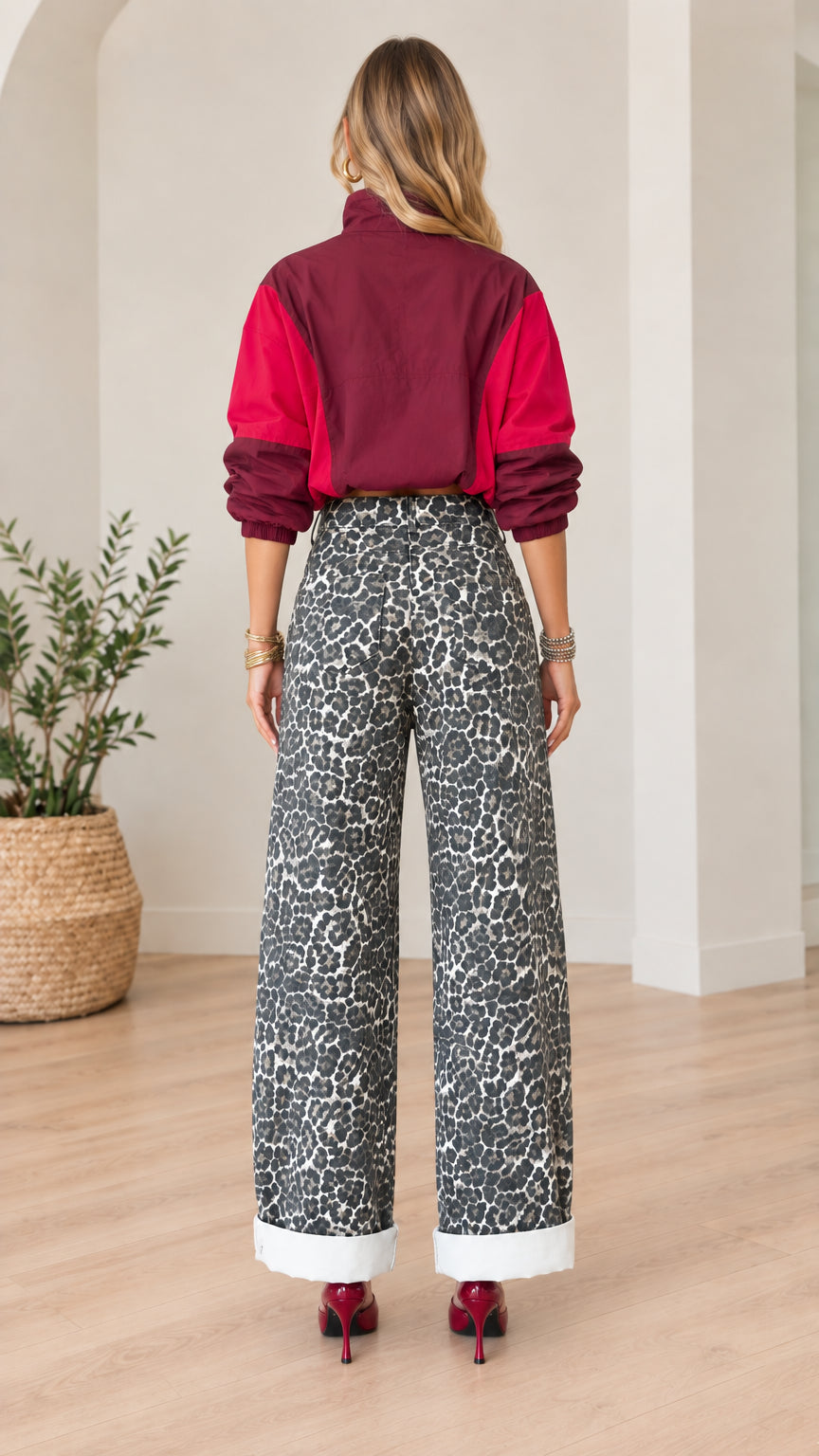 Back full view of woman wearing burgundy and magenta cropped pullover windbreaker and leopard pants