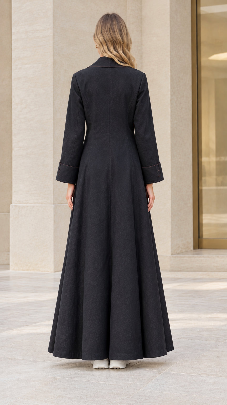 Back view of model showing fitted waist and sweeping flared hem on black maxi coat