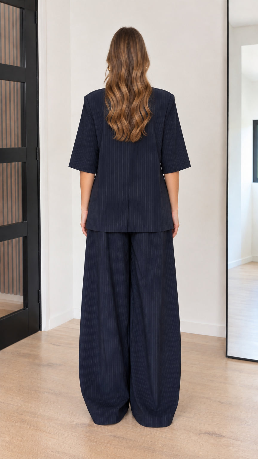 Back view of model wearing Navy Blue short sleeve top and wide-leg trousers set
