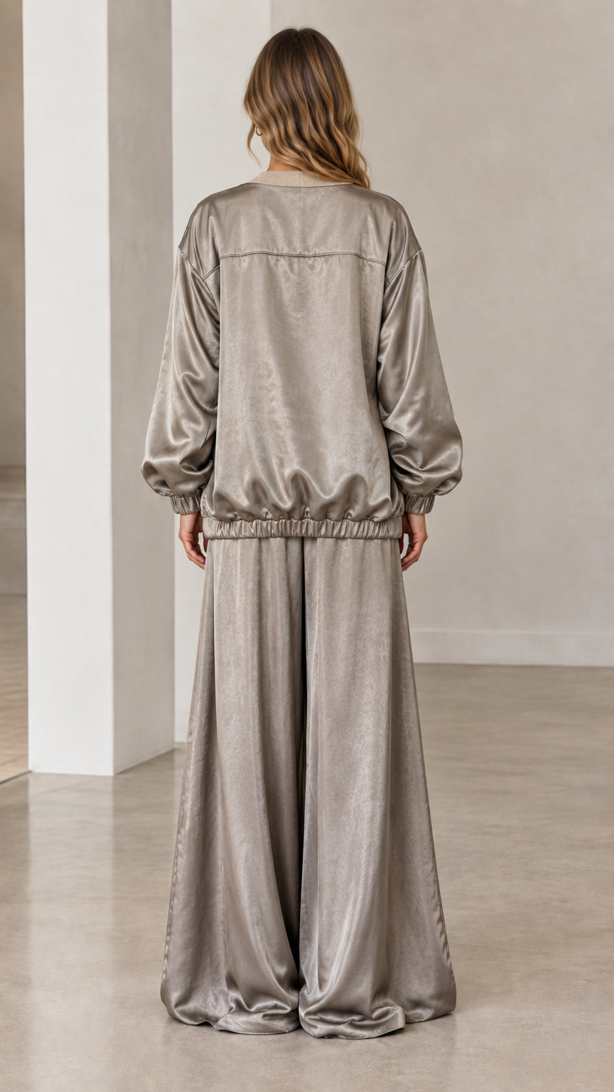 Back full-length view of woman in taupe satin wide-leg trousers and elastic-hem jacket