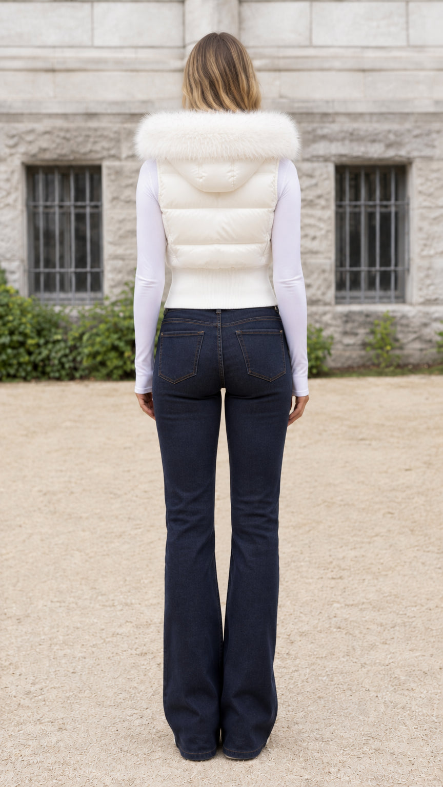 Back view of model wearing Ivory quilted hooded puffer vest and dark denim jeans