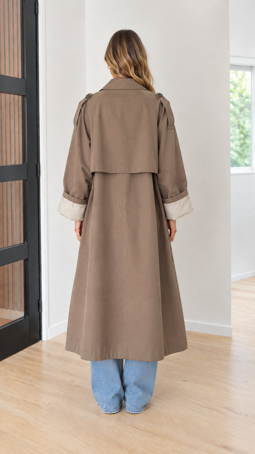 Back full-length view of taupe brown maxi trench coat highlighting back storm flap and vent