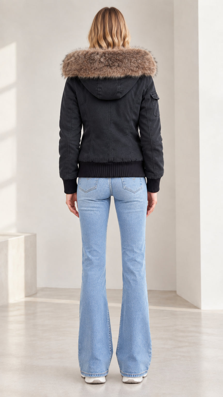 Back view of model wearing black hooded winter jacket showing ribbed waistband and hood