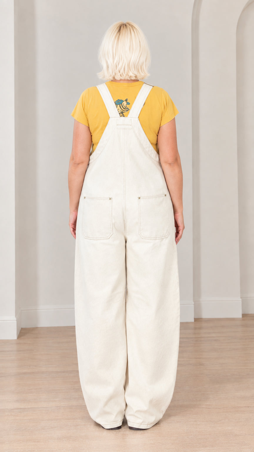 Back full-length view of woman wearing off-white dungaree overalls showing back pockets and cross straps