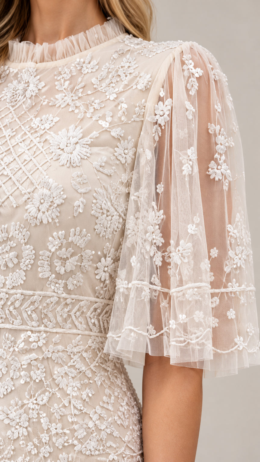 Close-up detail of champagne dress lace embroidery and flutter sleeve texture