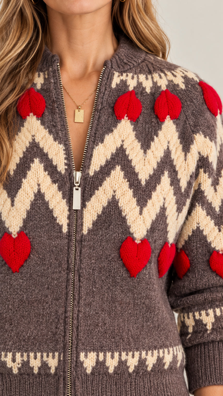 Close-up detail of textured red hearts and zipper on mocha brown knit cardigan
