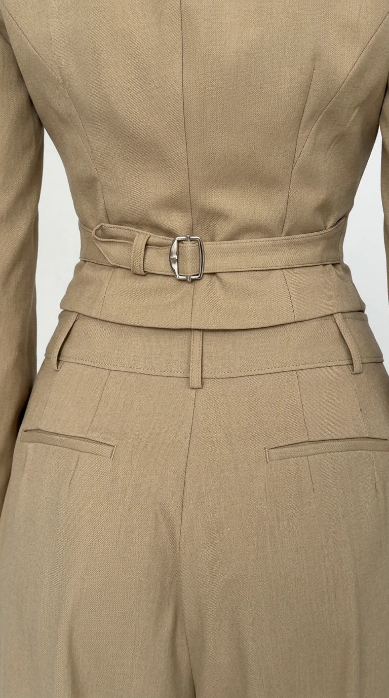 Close-up back detail of beige cropped blazer with adjustable buckle cinch strap and trouser waistband