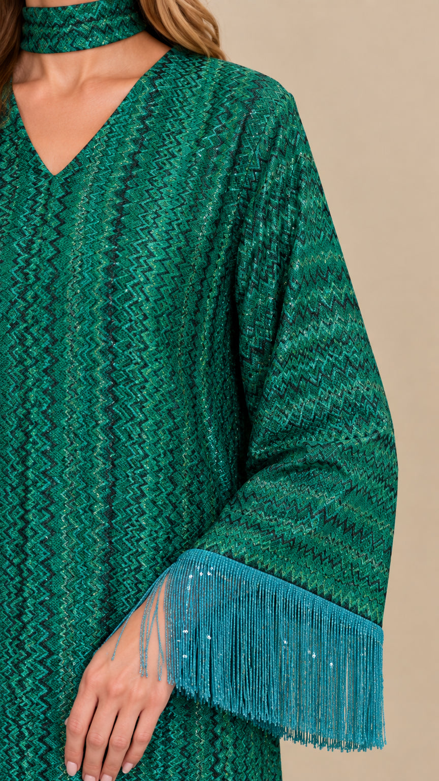 Close-up detail of emerald green textured chevron fabric, V-neckline with choker, and fringe trim on sleeve cuff