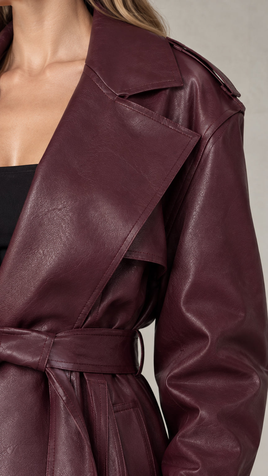 Close-up detail of the wide lapel collar and waist belt on the burgundy trench coat