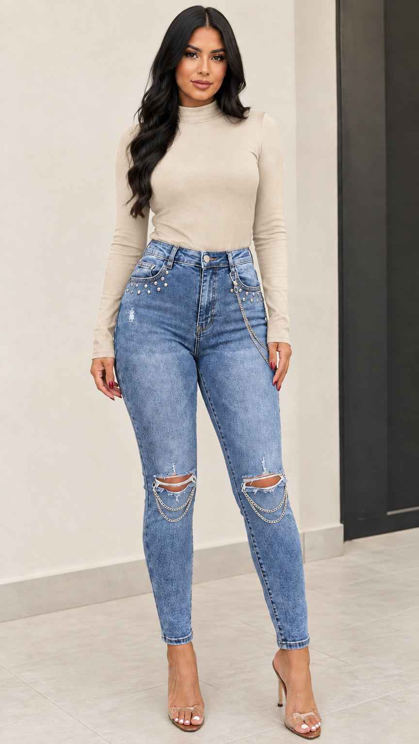 Front full view of medium blue chain distressed skinny jeans styled with a beige long sleeve top